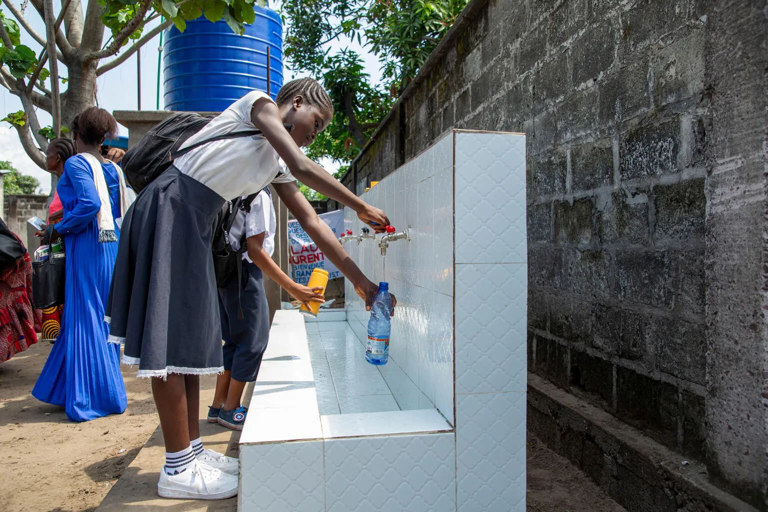 An 11-year-old girl fills a water bottle at her school in DR Congo.
