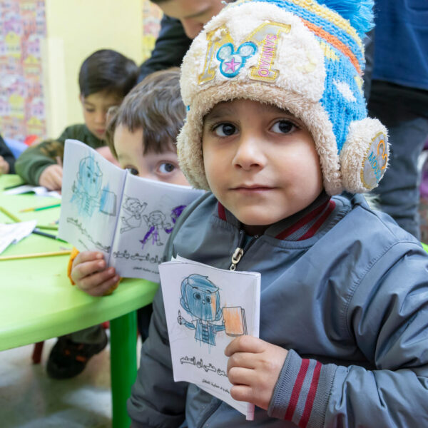Ghaith, 6, holds a booklet as he sits with other children in a psychosocial support session.