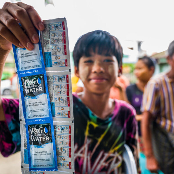 A boy shows packets of water purification sachets and tablets.