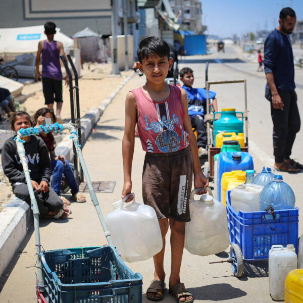 Haya Abu Hajer, 9 years old, holds a water container in both hands while looking at the camera. Clean water is scarce in Gaza, a basic child right.