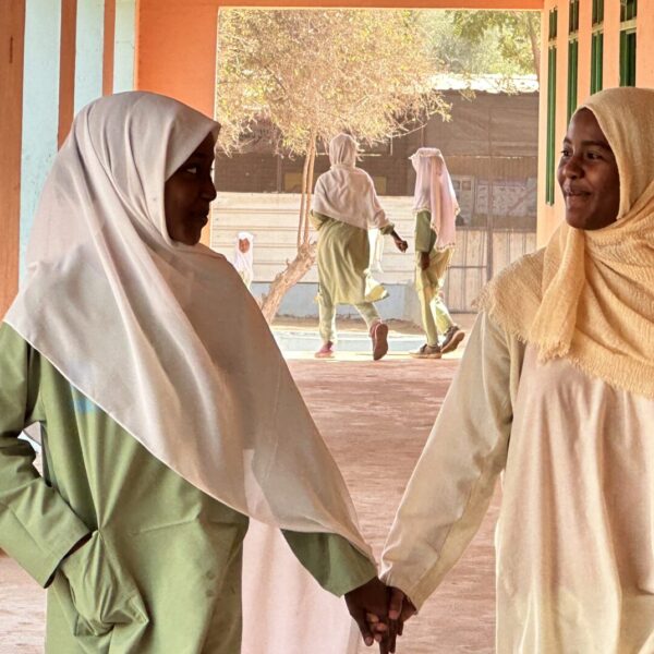 Two students hold hands happily in school.