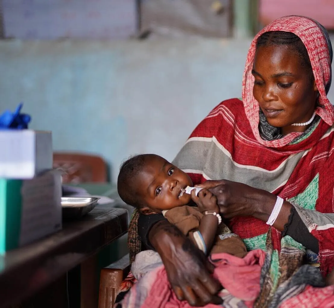Halimah feeds her 7-month daughter Asyaa with a nutrition supplement.