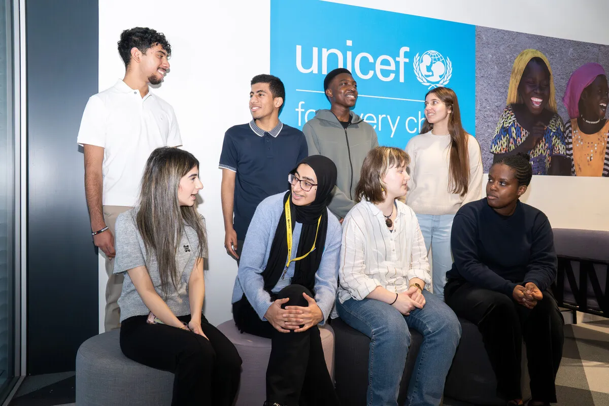 A group of eight young people post for a group photograph