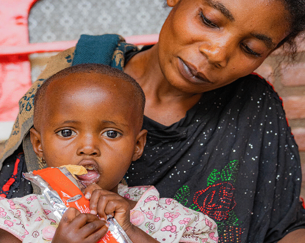 Naomie, 3, sits on her mother Chance Kapitula’s lap as she eats a therapeutic paste at the Shasha health centre in North Kivu province, DR Congo.