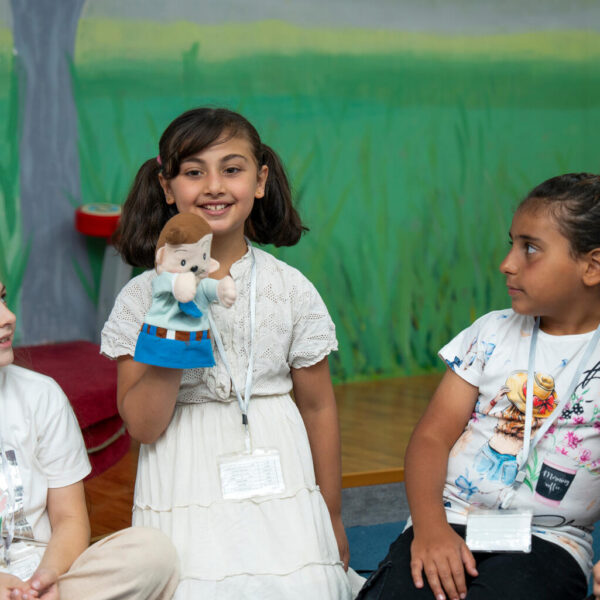 11 girl holds a puppet while attending a psychosocial support session on expressing feelings.