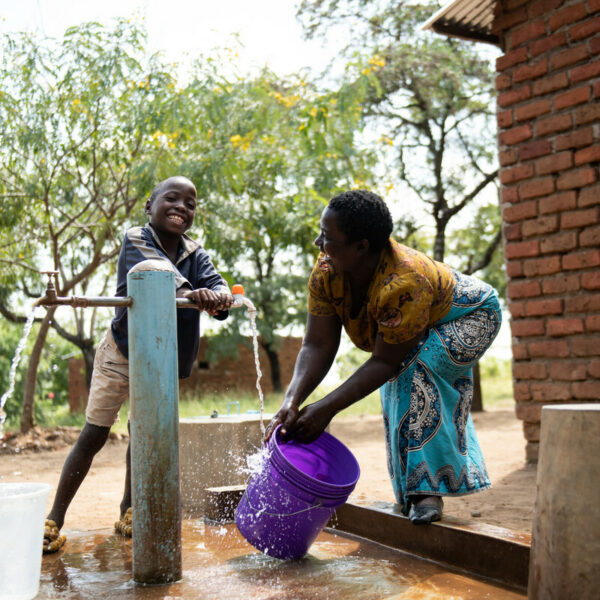 Joyce Mauzeni and her son 9-year-old Miracle Osman fetch water from a tap the children’s corner in Nankuyu Village in Blantyre southern Malawi on Sunday 21April 2024