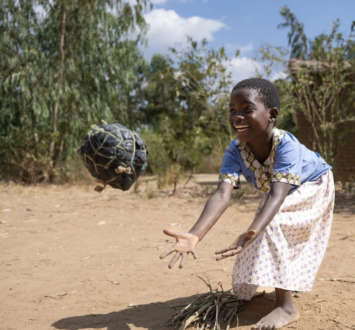 a young girl smiling whilst catching a ball