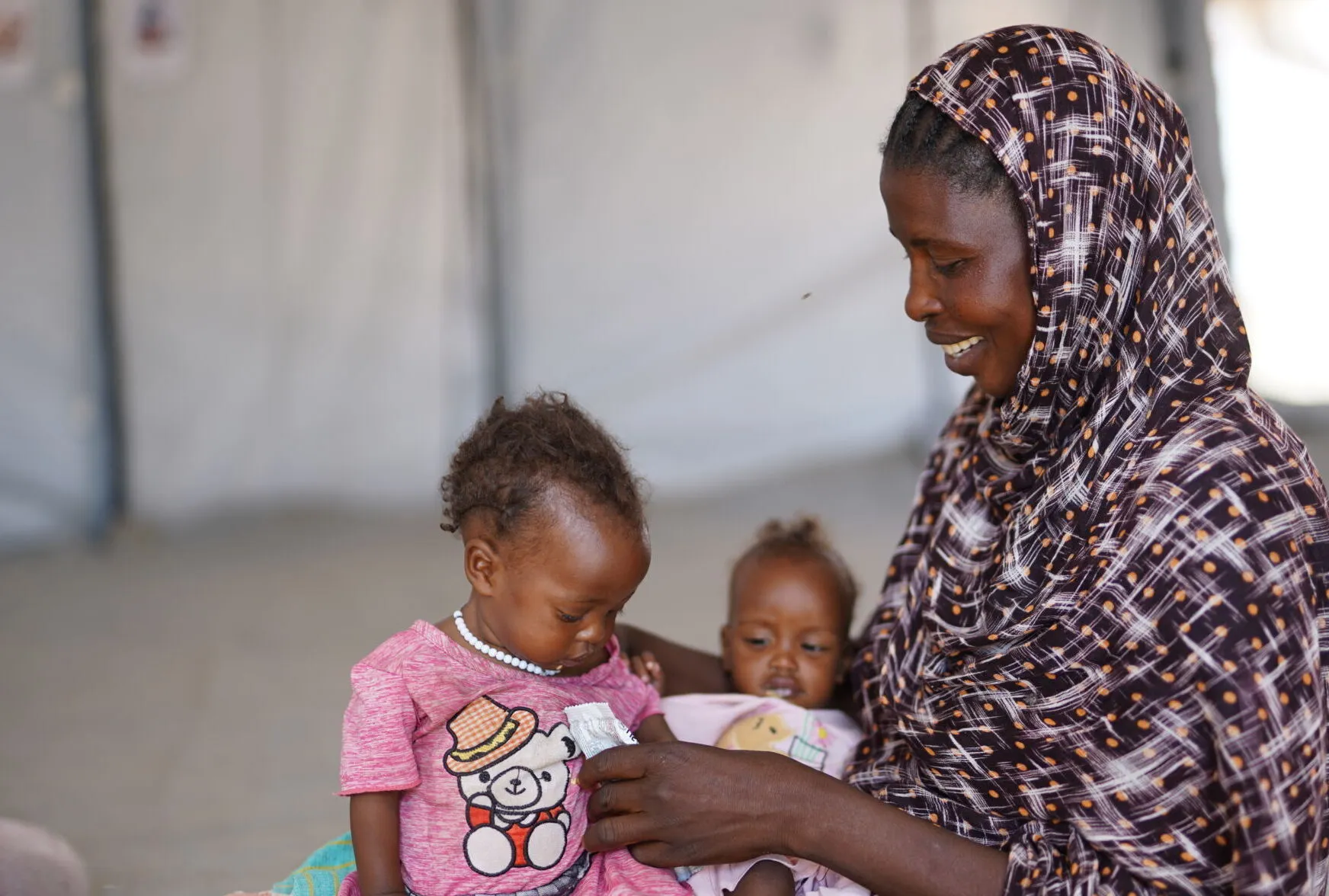 A mother feeds her twins with ready-to-use-therapeutic food at a UNICEF-supported nutrition centre in North Darfur.